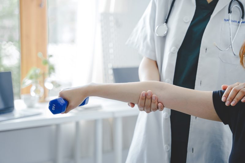 A woman receiving physical therapy in a bright clinical office.